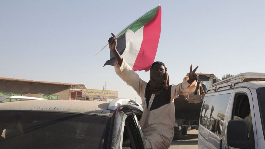 FILE: A Sudanese man gestures waving a Sudan flag in Merowe, Sudan, Saturday, Jan.11, 2025.