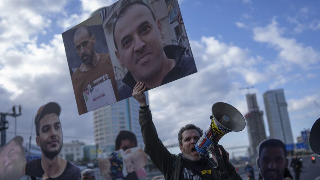 A demonstrator holds photos of freed Israeli hostage Eli Sharabi before and after his captivity.