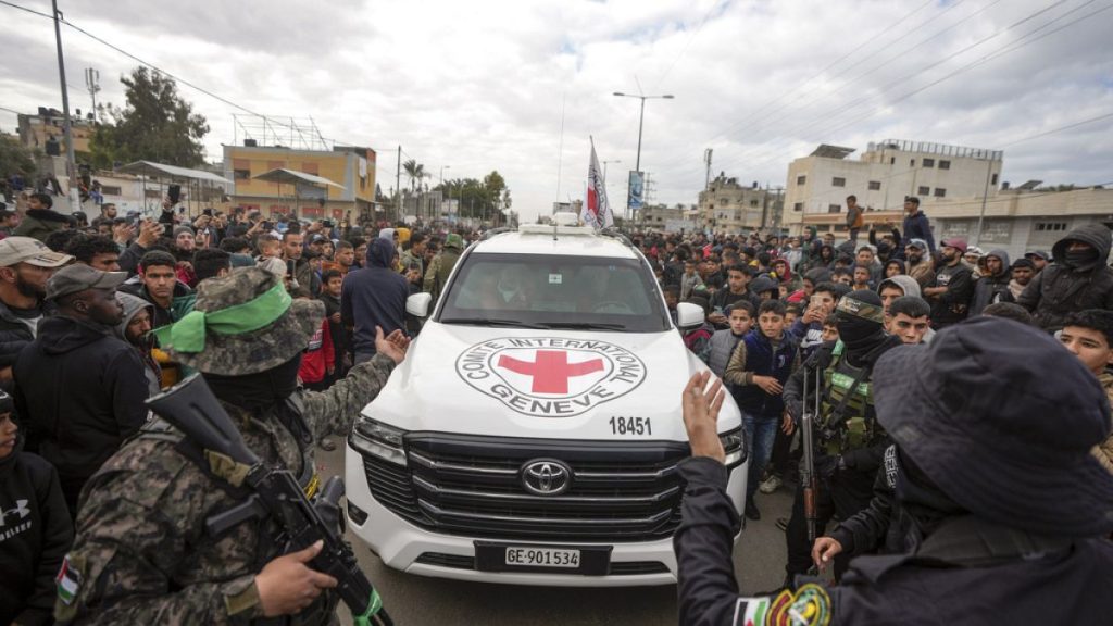 Palestinians gather as Hamas fighters escort Red Cross vehicles before handing over the three Israeli captives in Deir al-Balah, central Gaza Strip, 8 February, 2025.
