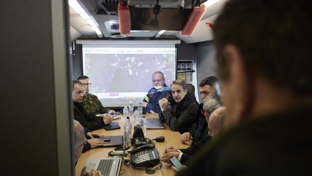 Greek Prime Minister Kyriakos Mitsotakis, center, gets an update during his visits at the temporary headquarters of emergency services.