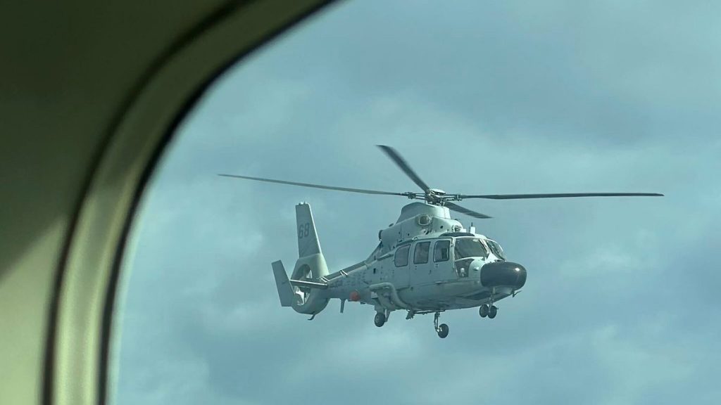 A Chinese military helicopter flies close to a Philippine Bureau of Fisheries and Aquatic (BFAR) aircraft above Scarborough shoal on 18 February, 2025.