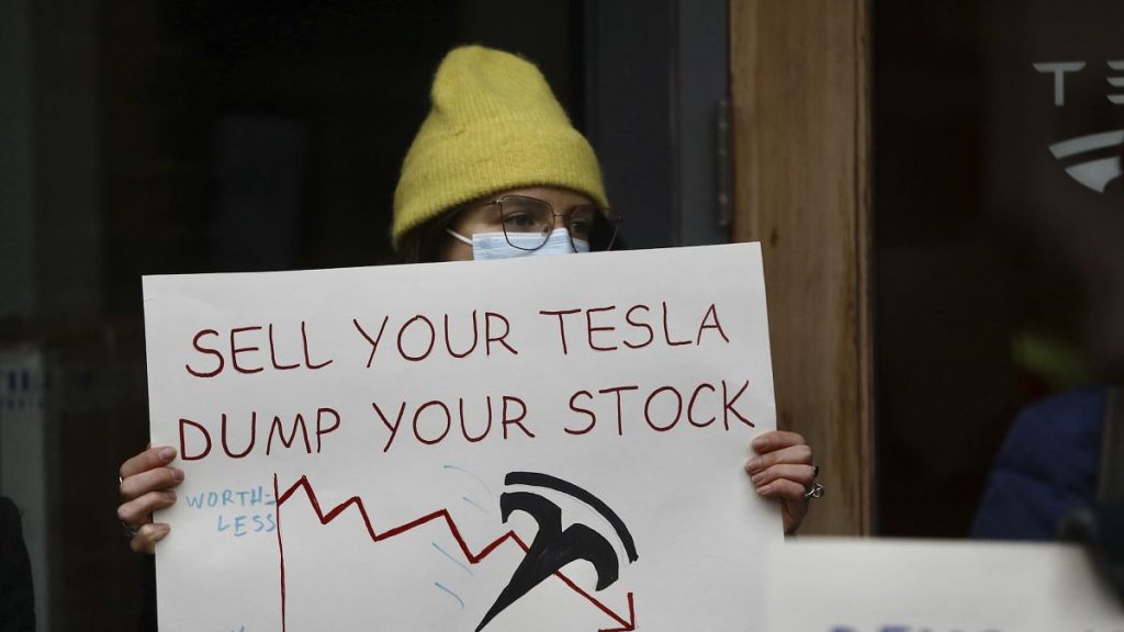 A protestor holding a sign outside a Tesla showroom in Seattle