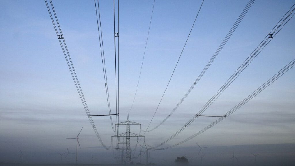 Wind turbines stand next to electricity pylons in the morning fog near Muencheberg, Germany, Thursday, Oct. 28, 2021.