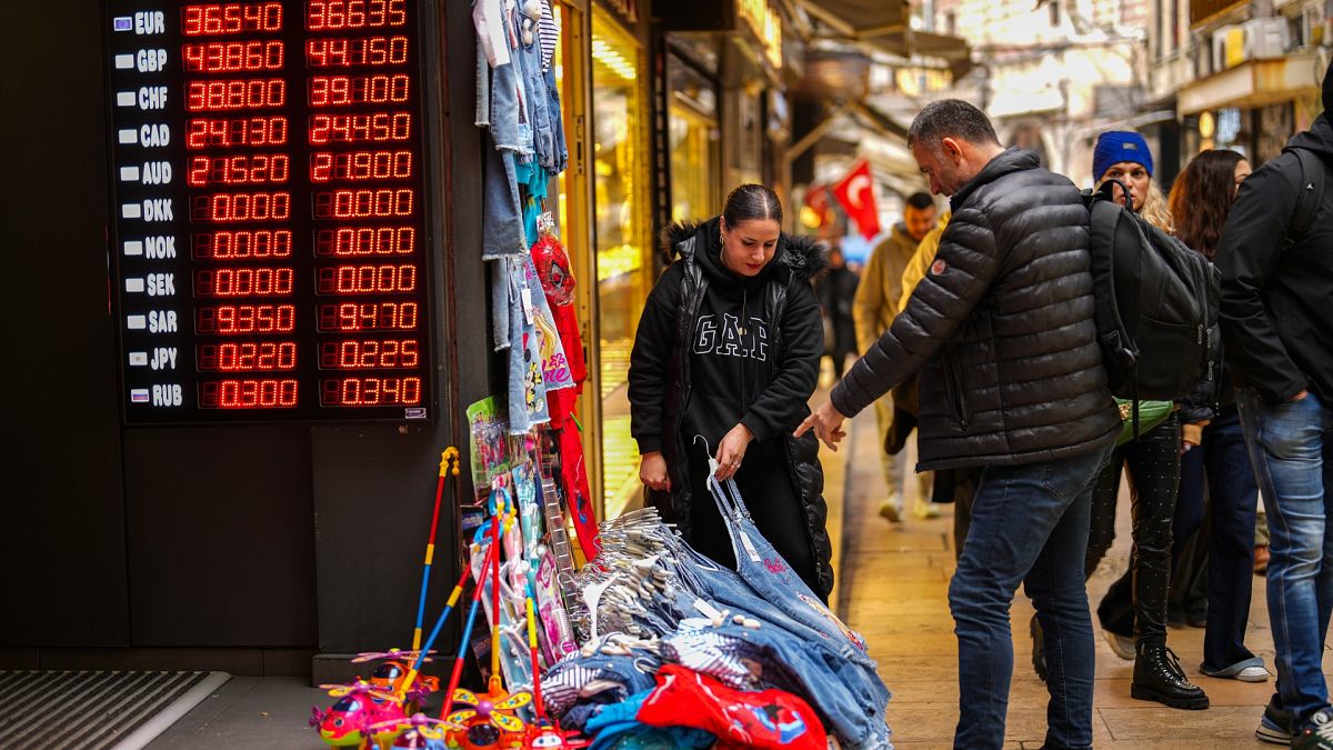 File photo of a  seller attending to a man, next to a currency exchange shop at Eminonu commercial area, in Istanbul, Turkey, Thursday, Dec. 26, 2024.