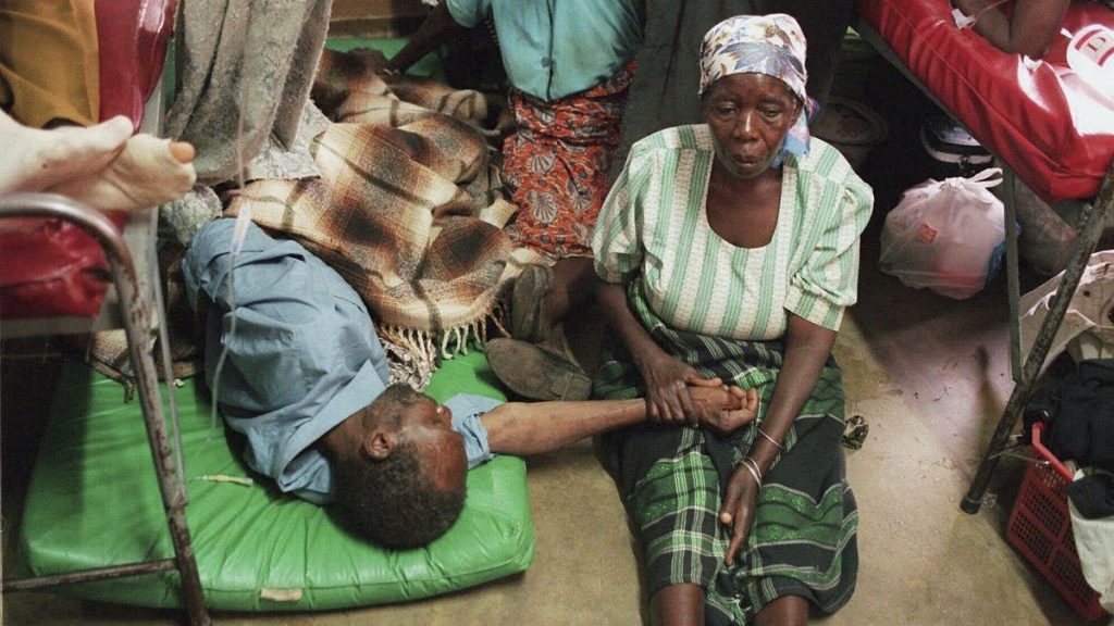 FILE - A woman holds the hand of a sick relative lying on the floor of the overcrowded Lilongwe Central Hospital, in Lilongwe, Malawi.