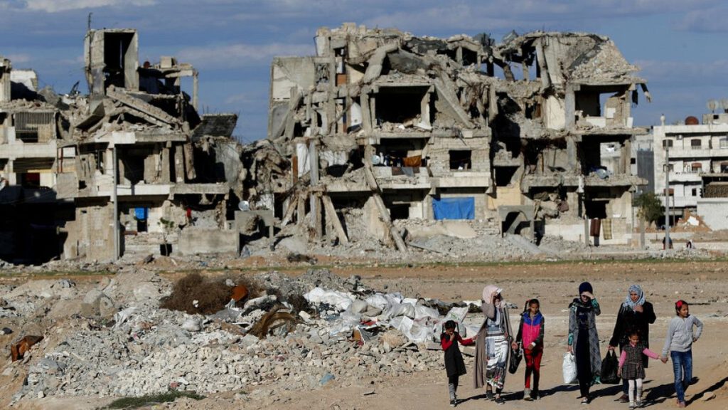FILE: Syrian citizens walk in front of buildings that were destroyed in Manbij, north Syria, March 31, 2018.