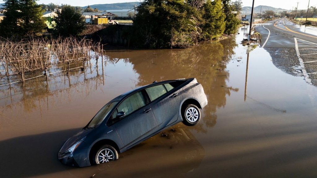 A vehicle is partially submerged in floodwater along State Route 121 following an atmospheric river event near Schellville in California.