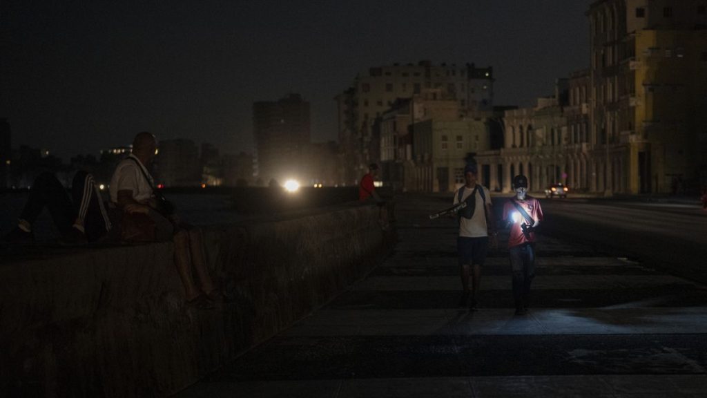 Residents walk on a street during a general blackout in Havana, Cuba, Friday, March 14, 2025. (AP Photo/Ramon Espinosa)