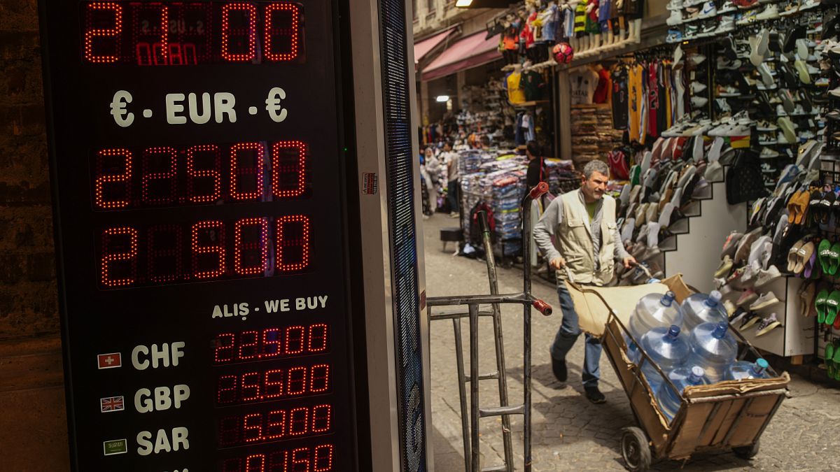A man carries bottles of water next to a currency exchange shop in the Eminönü commercial area of Istanbul.