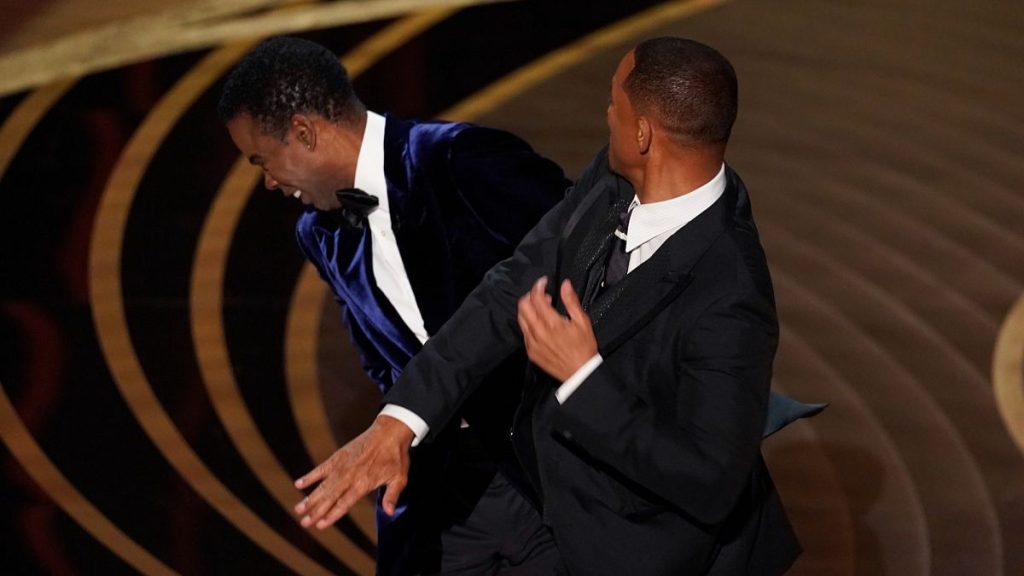 Will Smith, right, hits presenter Chris Rock on stage while presenting the award for best documentary feature at the Oscars on Sunday, March 27, 2022