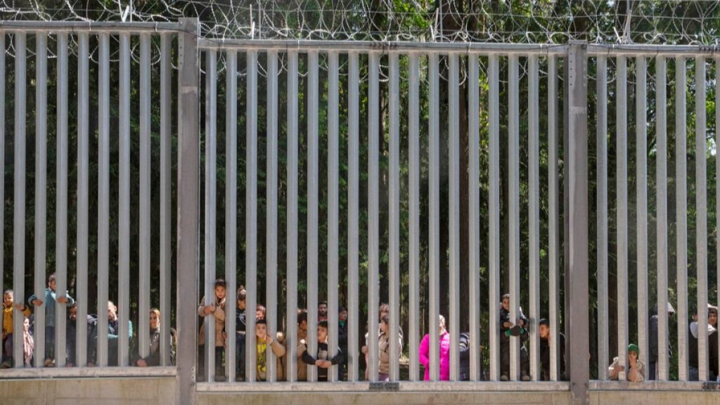 People seeking asylum look through the railings of a wall that Poland has built on its border with Belarus in Bialowieza, Poland, on May 28, 2023.