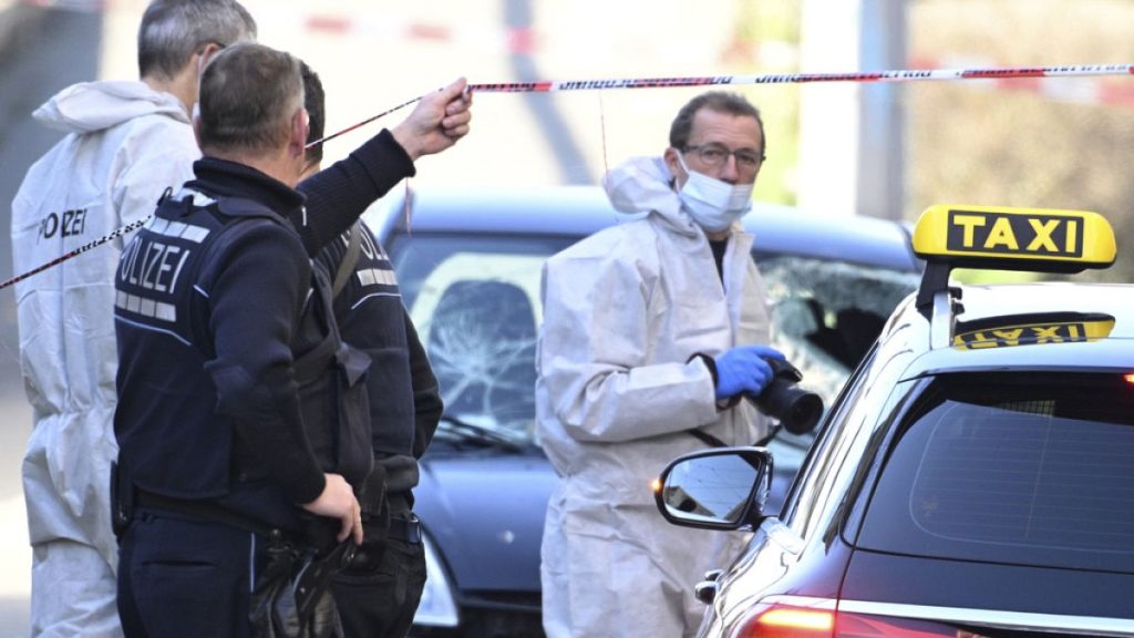 Forensics officers examine a damaged vehicle, background, at an access road to the Rhine bridge, in Mannheim, Germany, Monday March 3, 2025.