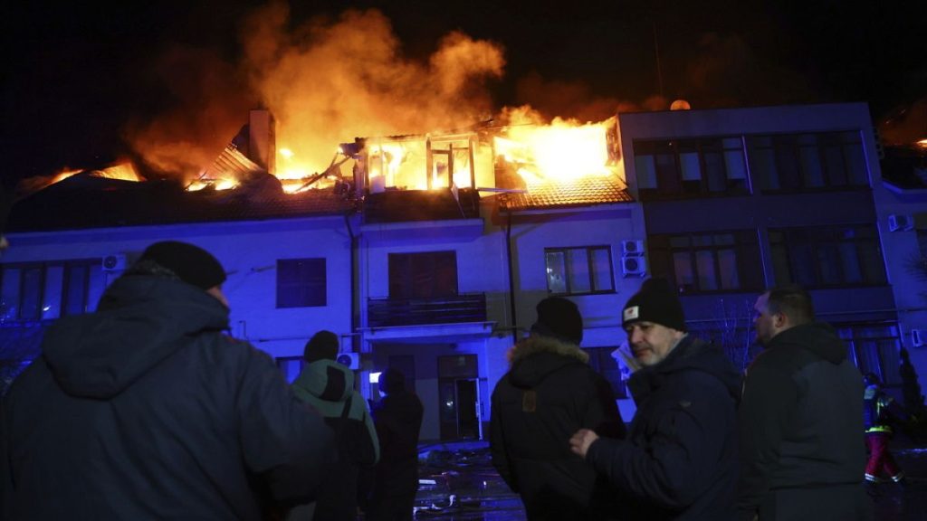 Local residents stand in front of burning house hit by a Russian drone strike on a residential neighborhood in Zaporizhzhia, Ukraine, Saturday, March 1, 2025.