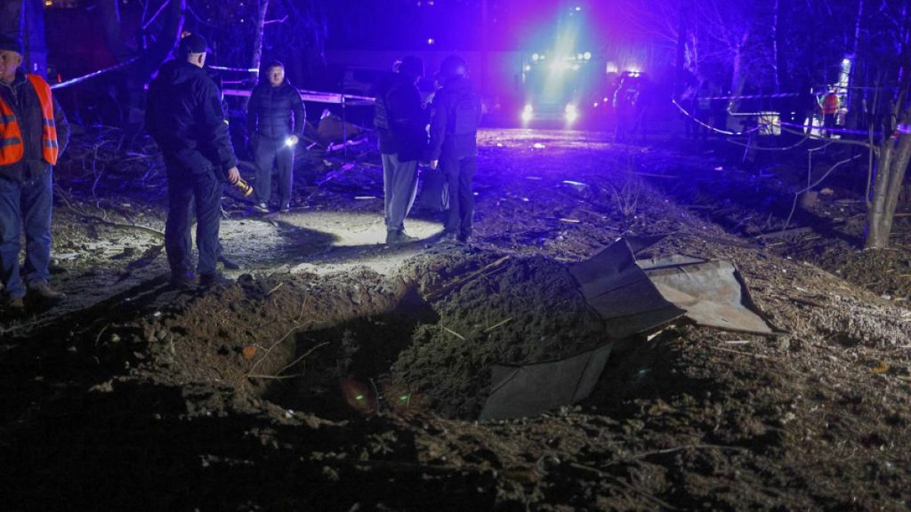 Police officers look at a crater made by a drone near apartment houses following Russia