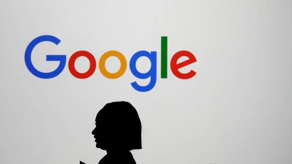 A woman walks by a giant screen with a logo at an event at the Paris Google Lab on the sidelines of the AI Action Summit in Paris.