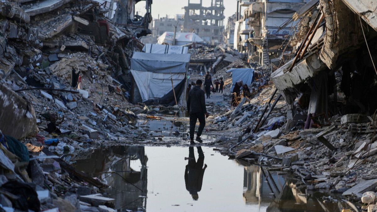 Palestinians walk amid the rubble of destroyed homes and buildings in Jabaliya, northern Gaza Strip on Friday, March 14, 2025.