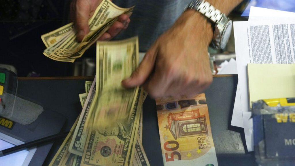 A cashier changes a 50 Euro banknote with US dollars at an exchange counter in Rome, Wednesday, July 13, 2022.