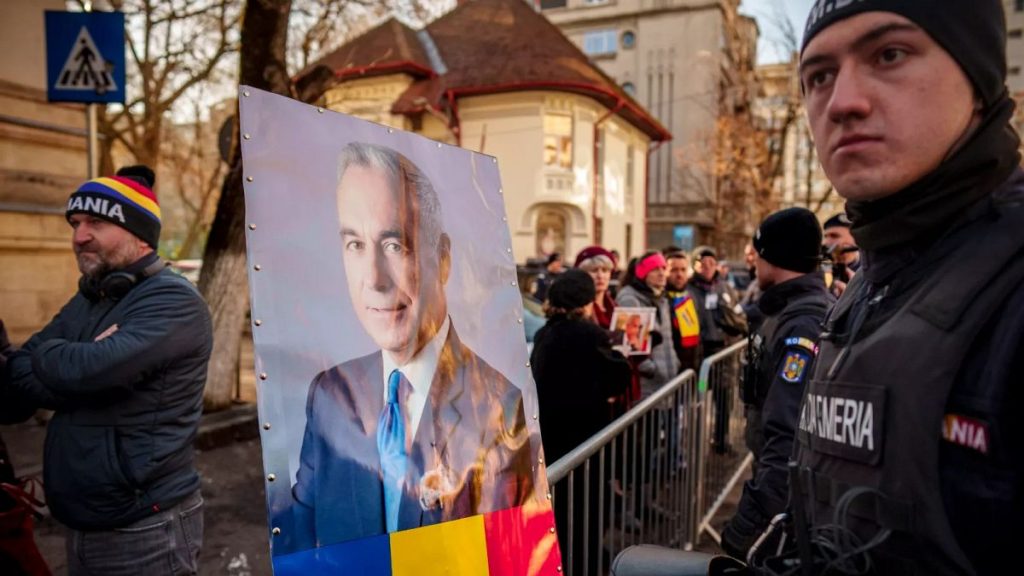 FILE: A portrait of Calin Georgescu, is placed on a crowd control fence by supporters waiting for his arrival at a district court in Bucharest, 5 March 2025