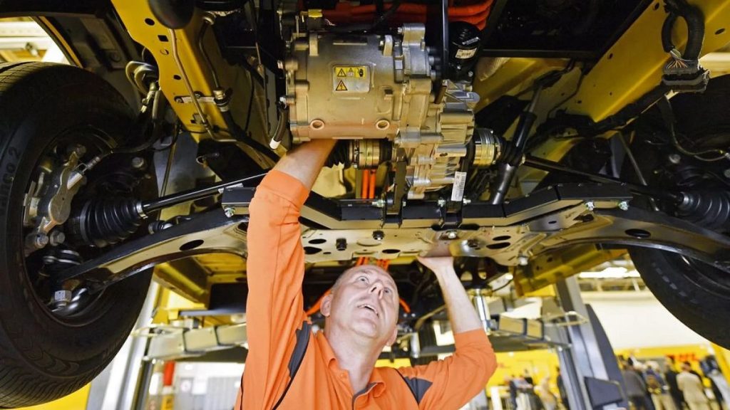 A worker looks at the small electric motor underneath a new Deutsche Post StreetScooter Work XL electric delivery van at the Ford car plant in Cologne, Germany, Oct. 9, 2018.