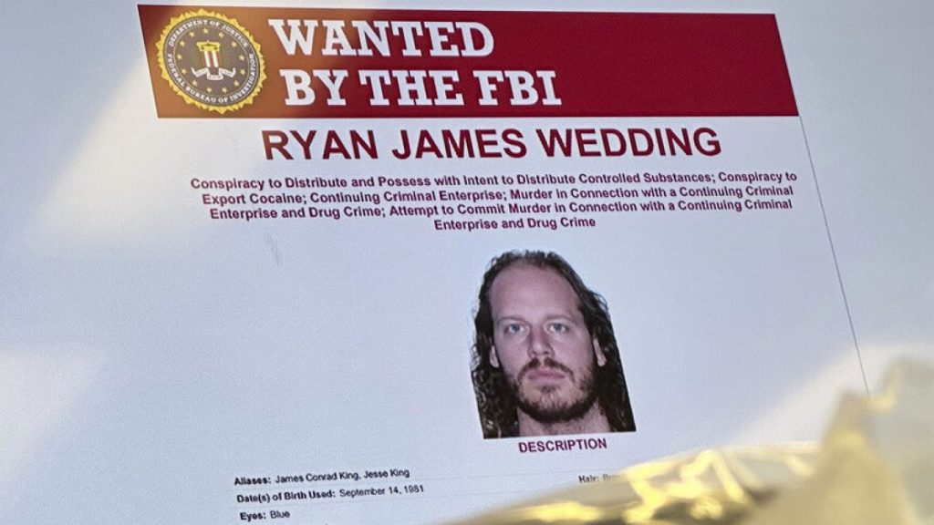 FILE: An image of former Canadian Olympic snowboarder Ryan Wedding is displayed on a video monitor during a news conference at the FBI offices in Los Angeles, Oct. 17, 2024.