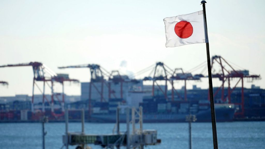 FILE - A national flag flies near a container port in Tokyo, 20 January 2022.