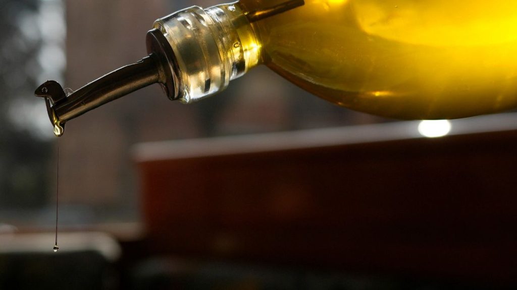 A person pours olive oil into a salad in Italy in March 2024.
