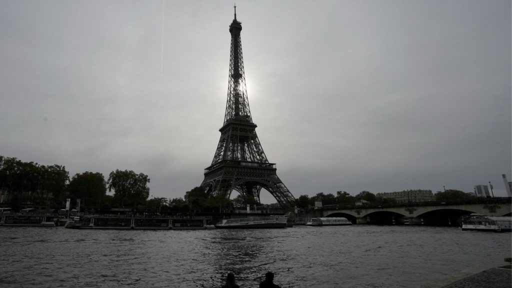 A couple sits by the river