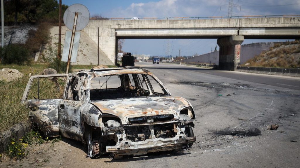 A burnt car remains in the middle of a empty road following the recent wave of violence between Syrian security forces and al-Assad loyalists, near Qardaha, 10 March 2025
