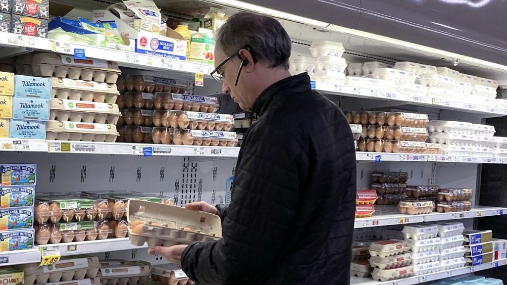 A shopper checks eggs before he purchases at a grocery store in Glenview, Ill.