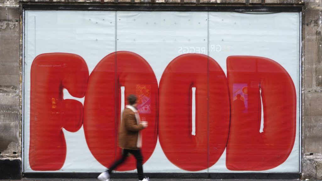 A pedestrian passes a shop hoarding in London Thursday, Feb. 20, 2025.