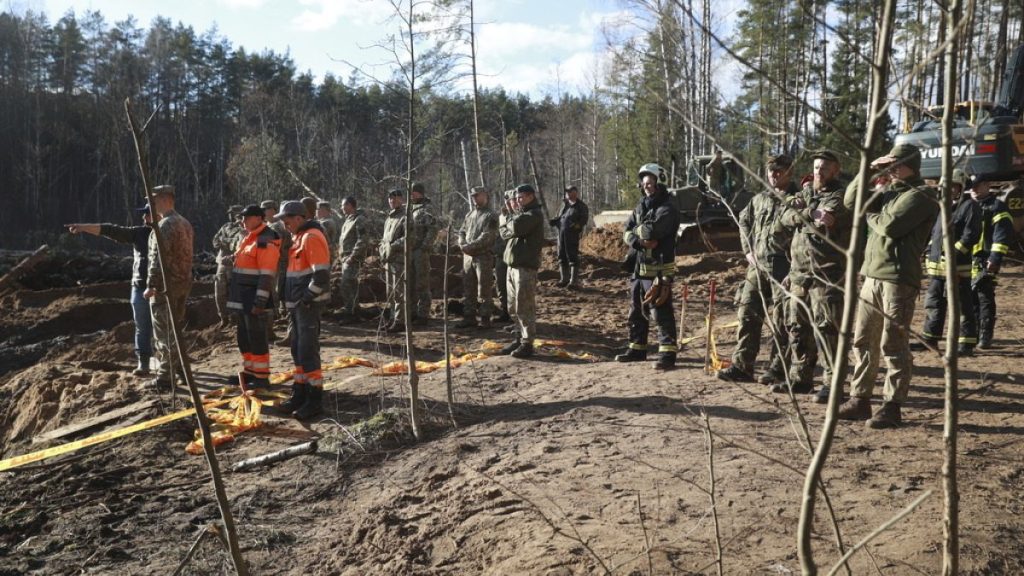 Lithuanian Army and emergency services personnel, discuss their plan to recover four U.S. soldiers in a U.S. Army M88 Hercules submerged under several meters of water