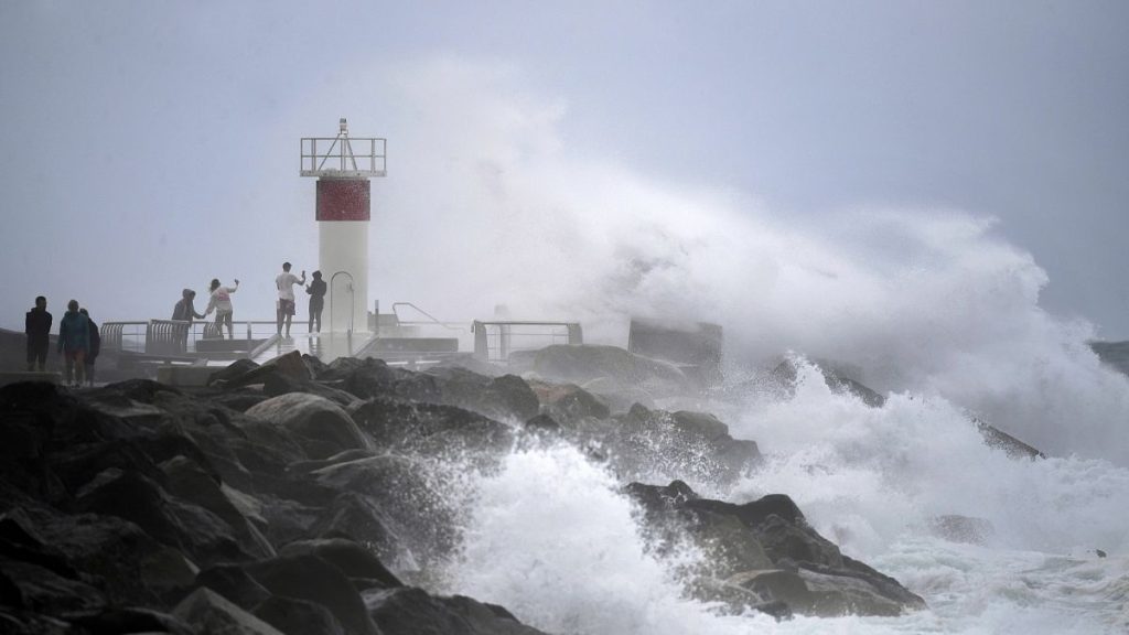 Waves crash onto rocks as people look on at the Spit, on the Seaway on the Gold Coast, Australia.