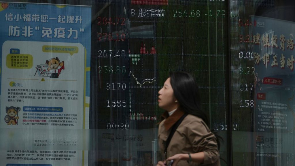 A woman walks by an electronic board displaying shares trading index at a brokerage house, in Beijing, 7 April 2025.