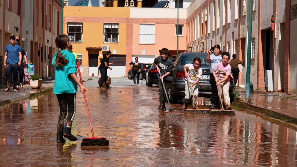 Young residents clear mud from the streets after heavy rains in Campanillas, Malaga, Spain, 18 March 2025.