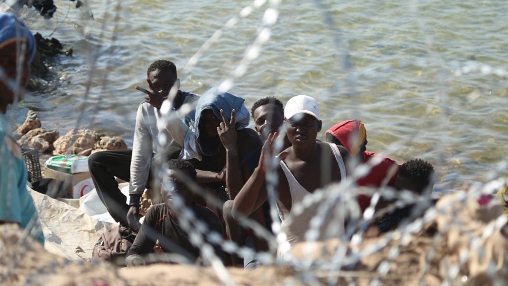 Migrants gather in an area near the Libyan-Tunisia border as Libyan security forces and Red Cross workers distribute food aid, 23 July, 2023