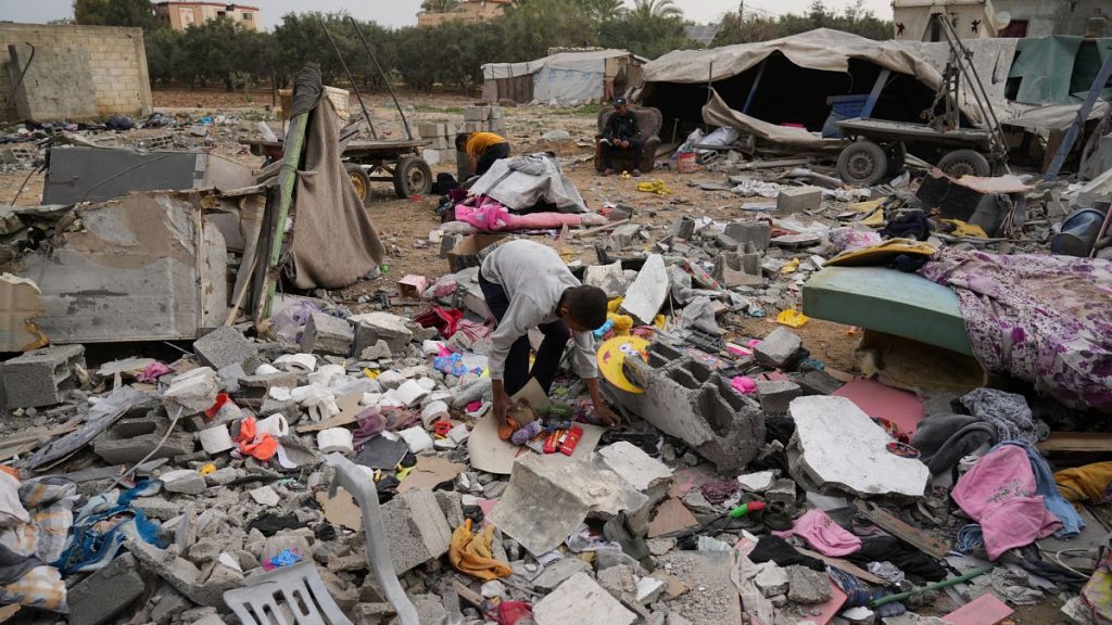 Palestinians collect their belongings from the rubble at the site hit by an Israeli strike in Deir al-Balah, 8 April, 2025