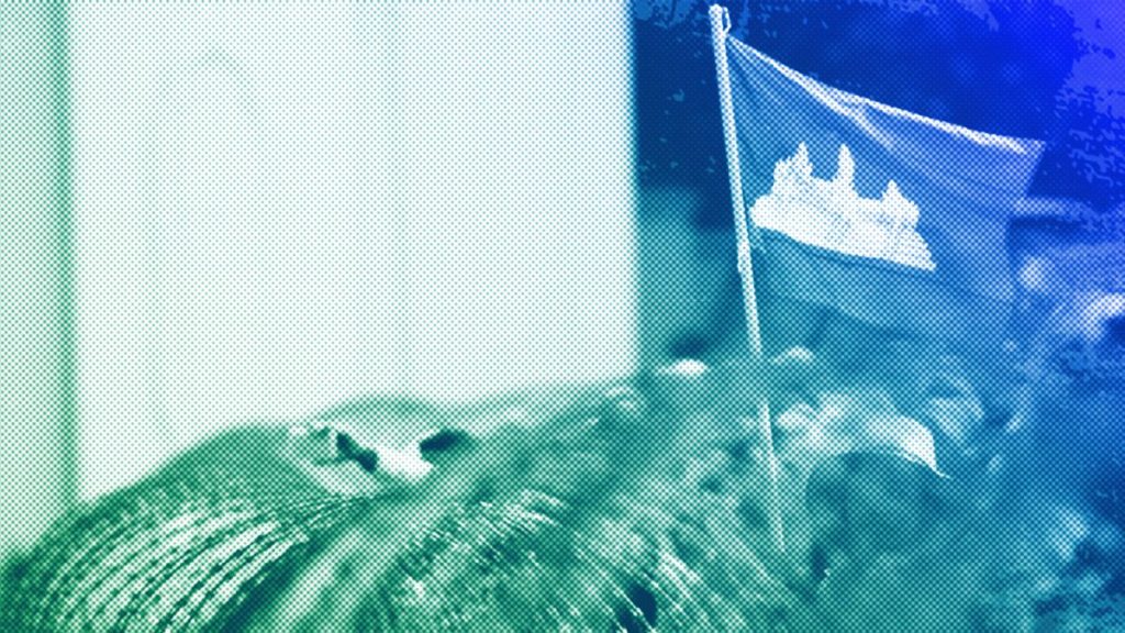 FILE: A Cambodian flag flutters above barbed wire set up by police near the Council of Ministers building while garment workers gather for a rally in Phnom Penh, December 2013