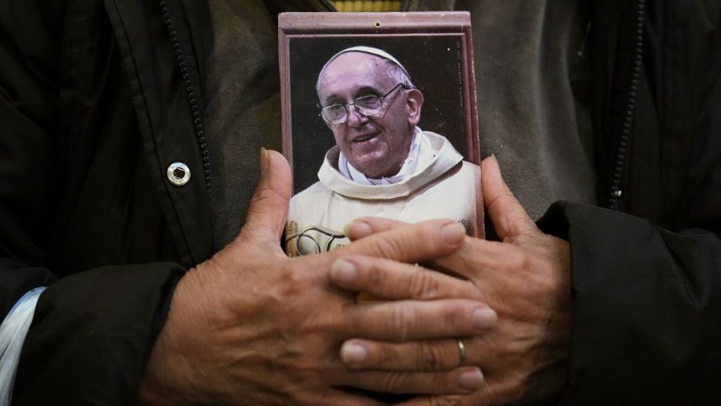 A faithful holds a portrait of late Pope Francis at the Basílica de San José de Flores in Buenos Aires, 21 April, 2025