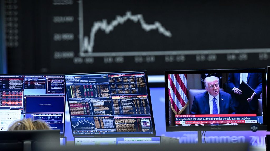 Behind a television monitor showing US President Donald Trump, the display board with the Dax curve shows falling share prices, in Frankfurt, Germany. 3 April 2025.