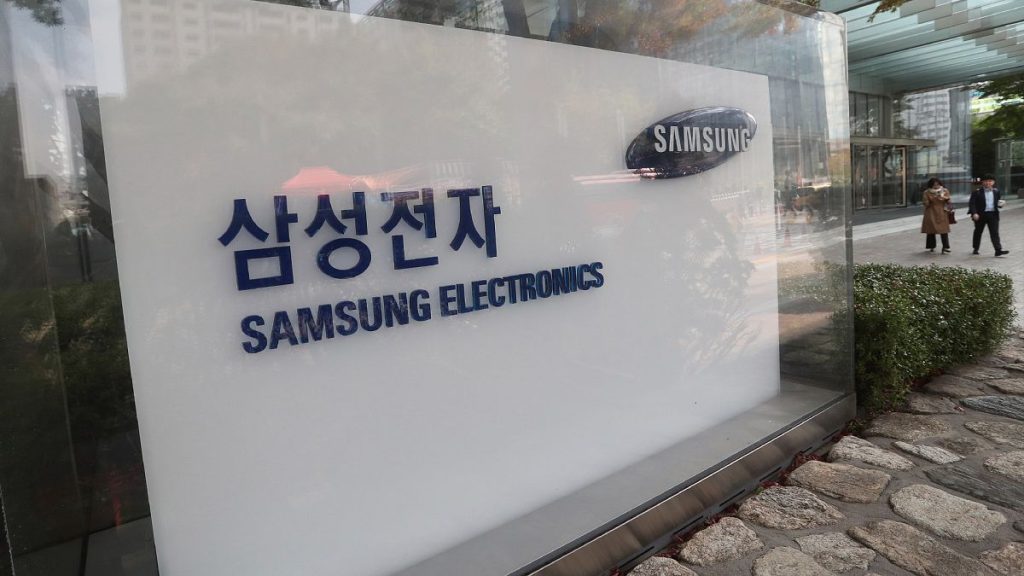 People walk near the logo of the Samsung Electronics Co. at its office in Seoul, South Korea, Thursday, Oct. 31, 2019.