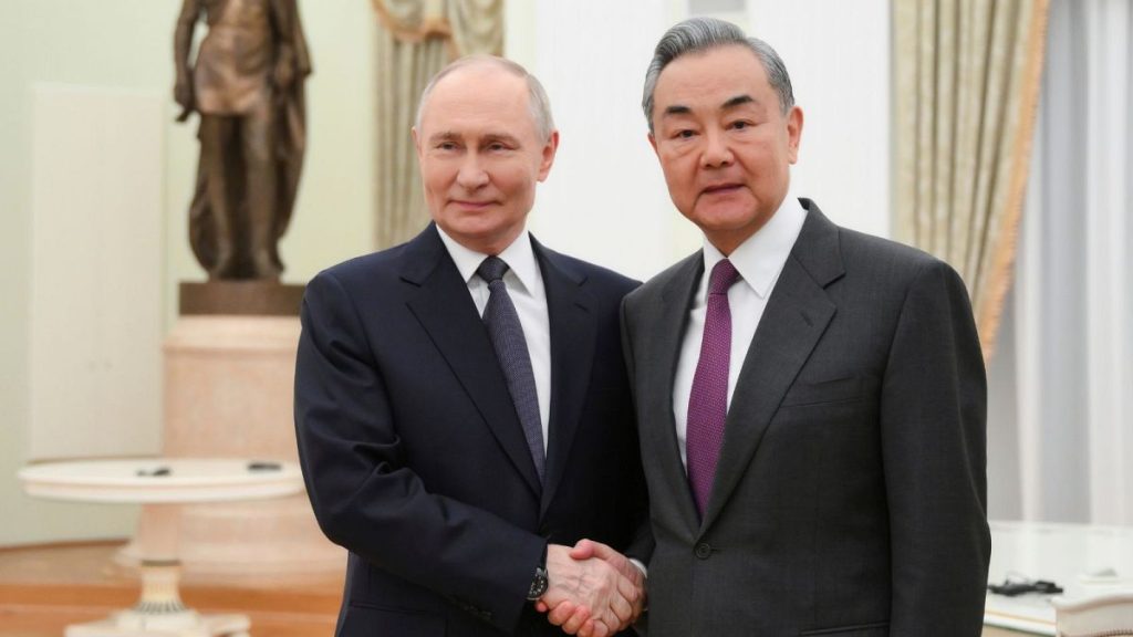 Russian President Vladimir Putin and Chinese Foreign Minister Wang Yi shake hands during their meeting at the Kremlin in Moscow.
