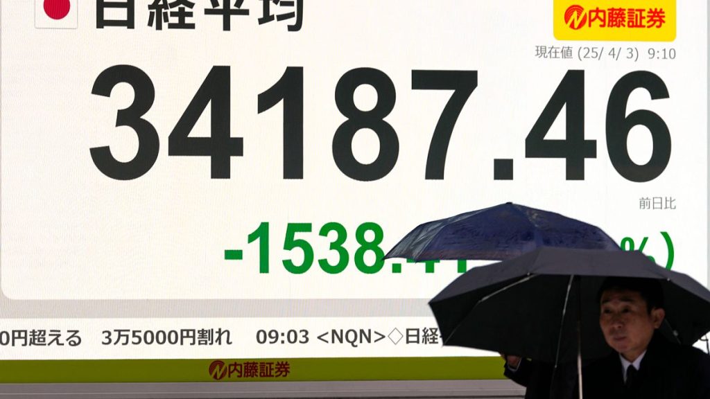 People walk past an electronic stock board showing the day