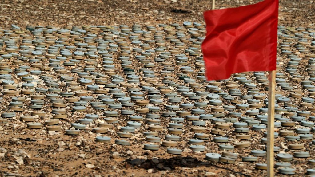 A red flag, a sign of danger is placed by removed landmines by the Libyan army to be destroyed later, during an operation to clear a landmine field near the coastal and border