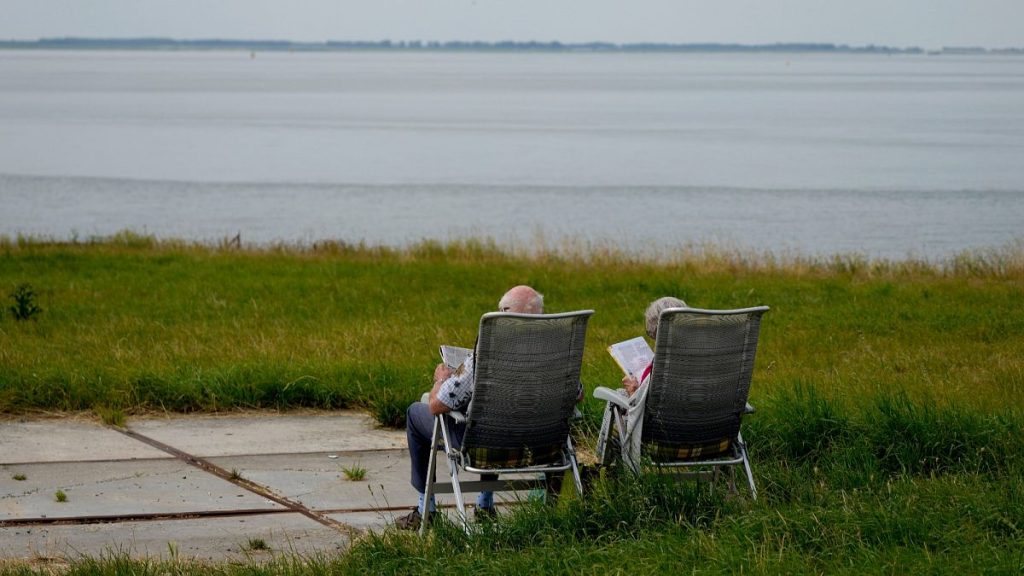 An elderly couple read as they sit on lawn chairs in front of the Schelde River in Bath, Netherlands, on Friday, July 22, 2022.