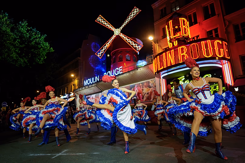 Des danseurs se produisent devant le cabaret du Moulin Rouge lors de l'inauguration du moulin à vent du théâtre à Paris, le 5 juillet 2024