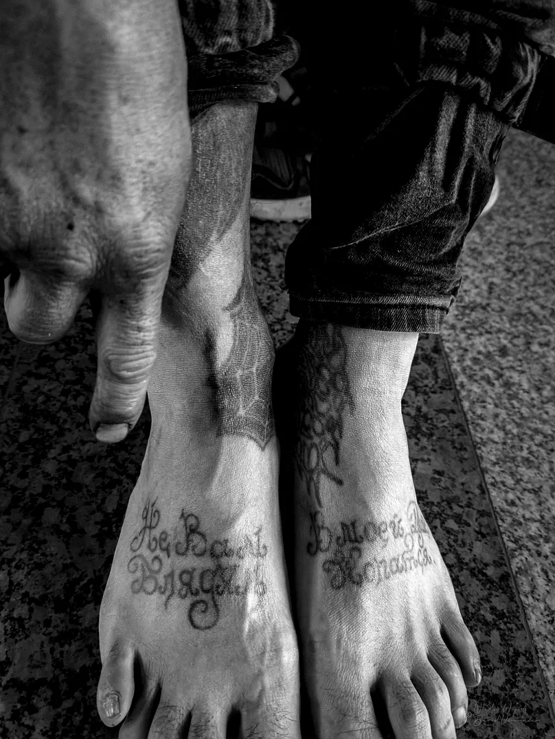 Un homme montre des tatouages sur ses pieds, dans le cadre de l'exposition « Entouré de criminels »