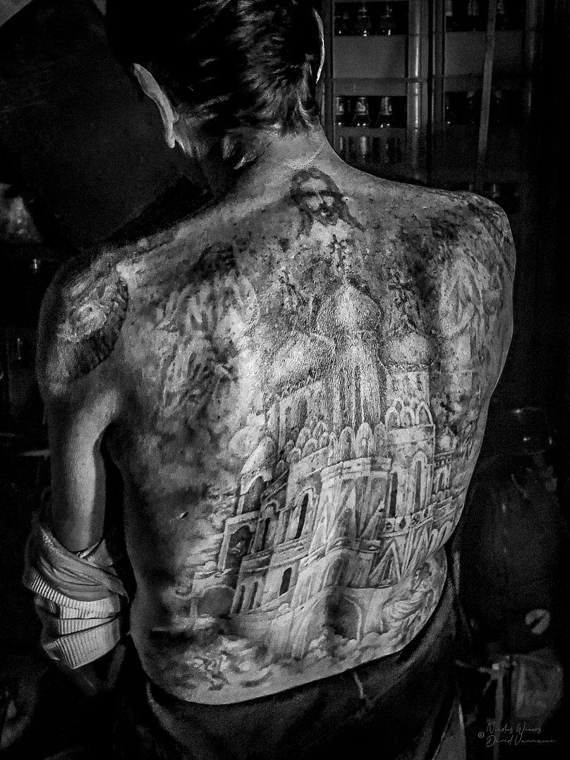 Un homme montre ses tatouages dans le dos, dans le cadre de l'exposition « Entouré de criminels »