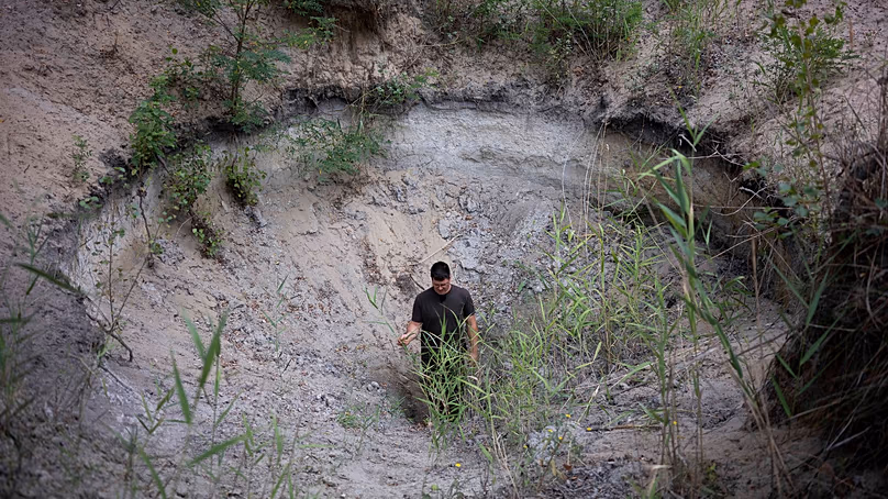 Oszkár Nagyapáti, agriculteur et membre des gardiens bénévoles de l'eau, se tient dans un trou à Kiskunmajsa, en Hongrie, le 29 juillet 2025.