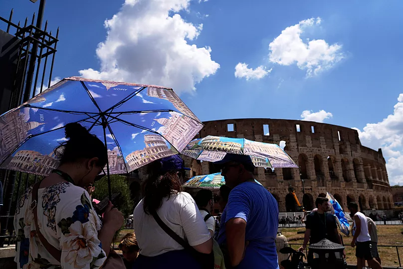 Les touristes utilisent des parapluies pour s'abriter de la chaleur lorsqu'ils font la queue pour visiter le Forum de Rome en juillet.