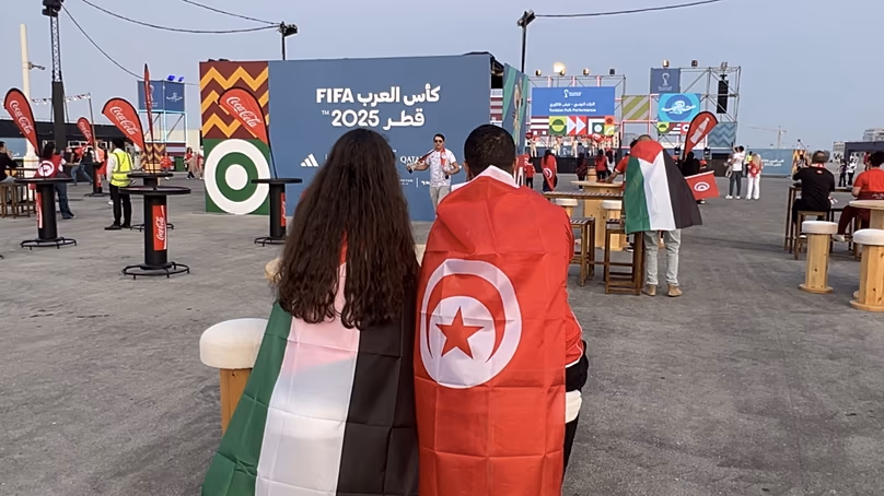 Un supporter tunisien et palestinien sont assis ensemble dans la fan zone du boulevard Lusail.